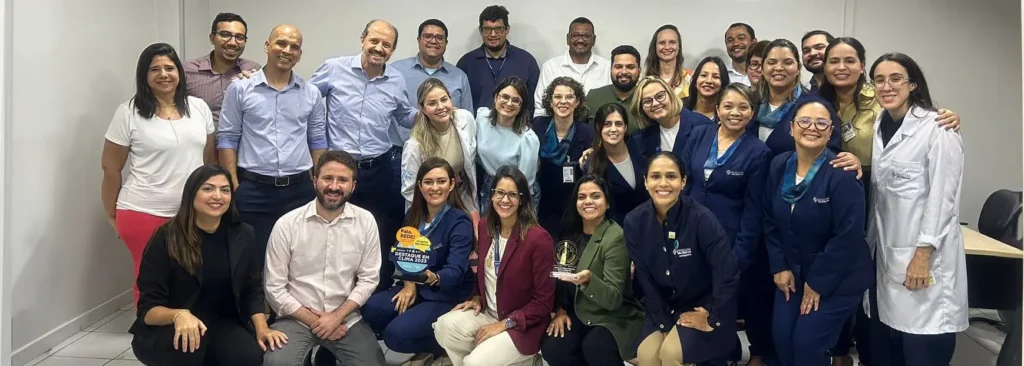 Time do Hospital São Marcos (PE), em 2024, celebrando a entrega do troféu de destaque na pesquisa de clima “Fala, Rede!”.